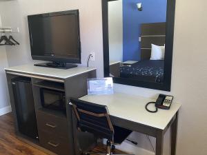 a room with a desk with a television and a mirror at Oasis Inn Sacramento- Elk Grove in Sacramento