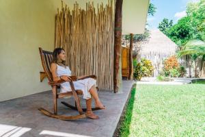 a man sitting on a wooden bench in front of a house at Hotel & Suites Oasis Bacalar in Bacalar