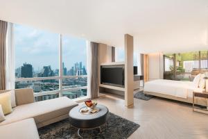 a living room with a white couch and a large window at Pathumwan Princess Hotel - SHA Extra Plus Certified in Bangkok