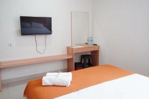 ein Schlafzimmer mit einem Bett und einem TV an der Wand in der Unterkunft UROOMS Tanah Abang in Jakarta