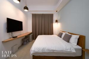 宜蘭市的住宿－Late Hours，卧室配有白色的床和平面电视。