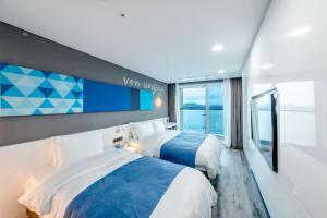 two beds in a room with a view of the ocean at Co-op City Hotel Seongsan in Seogwipo