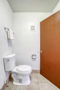 a bathroom with a toilet and a brown door at FairBridge Inn Express North Lima in North Lima