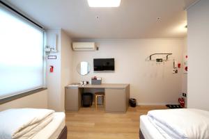 Habitación con 2 camas y escritorio con espejo. en K-Grand Hostel Dongdaemun en Seúl