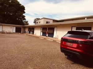 a red car parked in front of a building at Red Cedar Motel in Muswellbrook