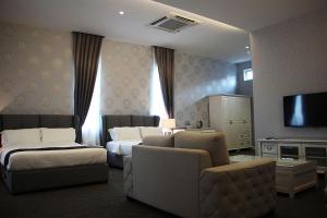 a hotel room with two beds and a couch and a tv at Casa Bianca in Kluang