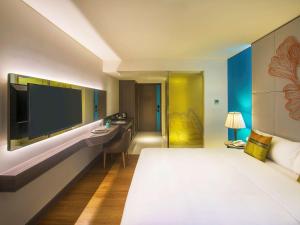 um quarto de hotel com uma cama e uma televisão de ecrã plano em ibis Styles Siem Reap em Siem Reap
