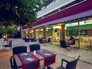 a restaurant with tables and chairs and people sitting at tables at Mercure Brive in Ussac