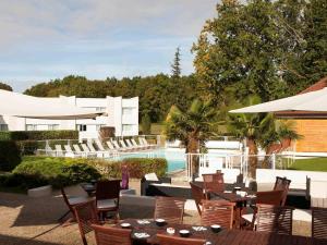 a patio with tables and chairs next to a pool at Novotel Fontainebleau Ury in Ury
