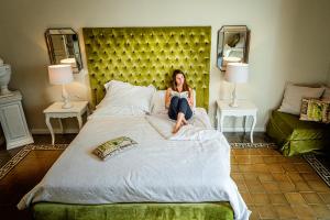 a woman sitting on a bed reading a book at B&B Palazzo Cerami in Catania