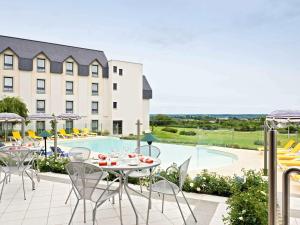 a patio with a table and chairs next to a pool at Novotel Amboise in Amboise