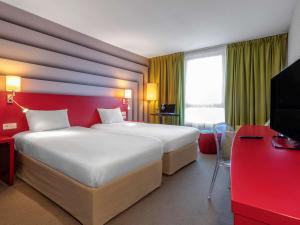 una camera d'albergo con un grande letto e una parete rossa di ibis Styles Avignon Sud ad Avignone