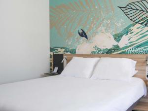 ナルボンヌにあるNovotel Narbonne Sud A9/A61の白いベッド1台付きのベッドルーム1室(壁に絵画付)