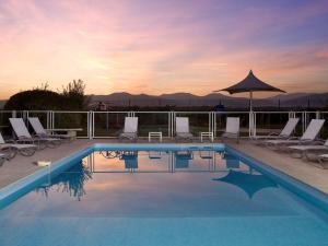 a swimming pool with chairs and an umbrella at Ibis Styles Colmar Nord in Colmar