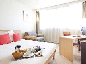 a hotel room with a bed with a tray of food on it at Novotel Pau Pyrénées in Lescar