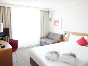 une chambre d'hôtel avec un lit et une chaise dans l'établissement Novotel Pau Pyrénées, à Lescar