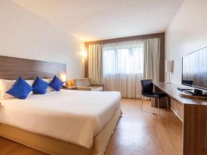 a hotel room with a large bed and a desk at Novotel Manaus in Manaus