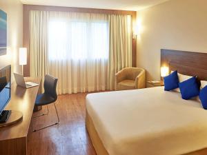 a hotel room with a large bed and a desk at Novotel Manaus in Manaus