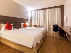 a hotel room with two beds and a desk at Novotel Manaus in Manaus
