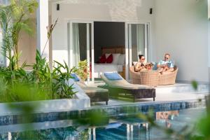 富國的住宿－水星富國島別墅度假村，一群人坐在泳池边的藤椅上