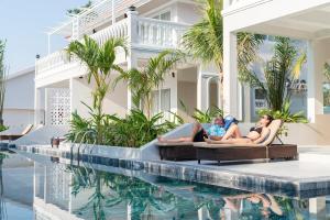 富國的住宿－水星富國島別墅度假村，两名妇女躺在游泳池旁边的躺椅上