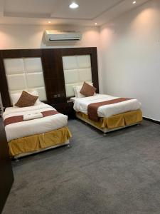 two beds in a hotel room with two bedsskirts at Rosa Aparthotel in Buraydah