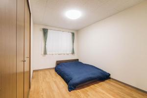 - une chambre avec un lit bleu et une fenêtre dans l'établissement STAY IN PASSION, à Asahikawa