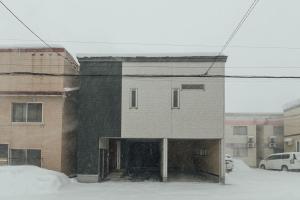 a building on a street with snow on the ground at STAY IN ASAHIBASHI Asahikawa in Asahikawa