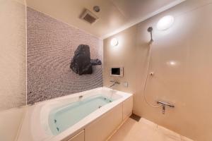La salle de bains est pourvue d'une baignoire avec un mur en pierre. dans l'établissement Hotel & Spa Lotus (Adult Only), à Kyoto