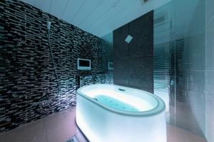 a bathroom with a bath tub and a glass shower at Hotel Eldia Modern Kobe(Adult Only) in Kobe