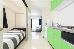 um quarto com uma cama e uma cozinha com armários verdes em Cocostay KO Residence Sennichimae#603ココステイ ケーオーレジデンス センニチマエ#603 em Okayama