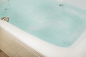 een wit bad gevuld met water in de badkamer bij Hotel Eldia Modern Kobe(Adult Only) in Kobe