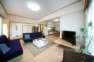 a living room with a blue couch and a tv at Exsaison house Kumoji in Naha