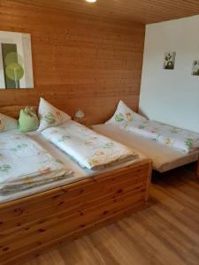 two beds in a room with wooden walls at Landhaus Erna in Böbrach +58 photos