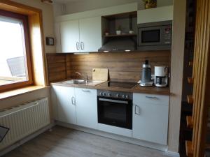 ノルトシュトラントにあるFerienwohnungen im Osterkoogの白いキャビネット、シンク、電子レンジ付きのキッチンが備わります。