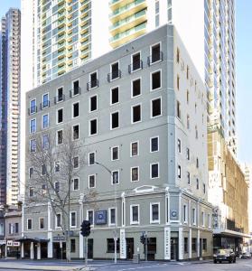 a gray building on a city street with tall buildings at Hotel Sophia in Melbourne