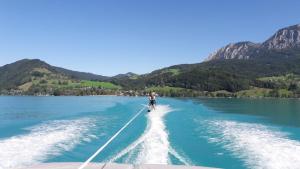 Ein Mann wird auf einem Boot auf dem Wasser gezogen. in der Unterkunft Biohof Schwanser in Steinbach am Attersee