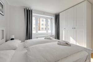 2 weiße Betten in einem weißen Schlafzimmer mit Fenster in der Unterkunft Wave Apartments - Grobla Old Town in Danzig