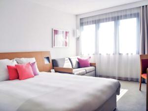 グダニスクにあるノボテル グダニスク セントラムの大きなベッドとソファが備わるホテルルームです。