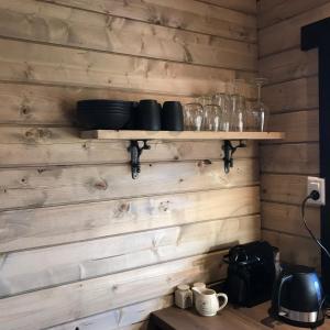 una cocina con paredes de madera y estanterías con tazones y vasos en Landelijk gelegen houten huisje, en Opperdoes