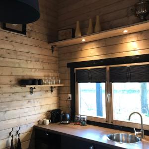 a kitchen with wooden walls and a sink and a window at Landelijk gelegen houten huisje in Opperdoes