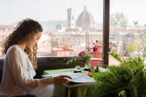 een vrouw aan een tafel met een boek bij Antica Torre Di Via Tornabuoni 1 in Florence