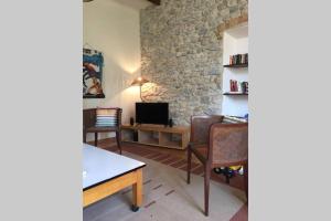 een woonkamer met een tv en een tafel en stoelen bij Les pieds dans l'eau - Gîte de L'olivier - Plage privée in Blacons