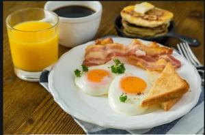 a plate of eggs bacon and toast with a glass of orange juice at OYO 279 Deli Homestay in Medan
