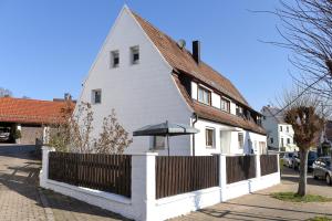 a white house with a fence and an umbrella at Wohlfühloase Brombachsee in Pleinfeld