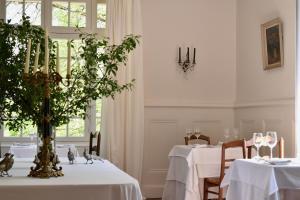 uma sala de jantar com duas mesas com toalhas de mesa brancas em Manoir de Plaisance em Benon