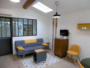 a living room with a blue couch and a tv at l appentis du chai in Roujan