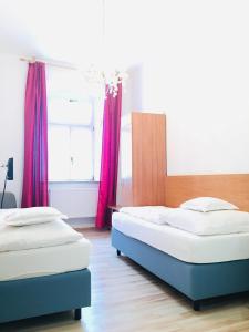 Hotel Bairischer Hof في ماركتردفيتس: سريرين في غرفة نوم مع ستائر حمراء