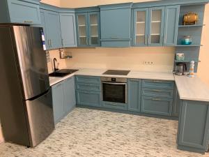 a kitchen with blue cabinets and a stainless steel refrigerator at Апартаменты Золотой Бугаз in Karolino-Buhaz