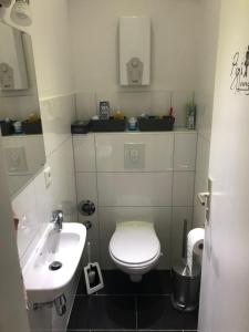 La salle de bains est pourvue de toilettes blanches et d'un lavabo. dans l'établissement Micha's Ferienwohnung, à Duisbourg